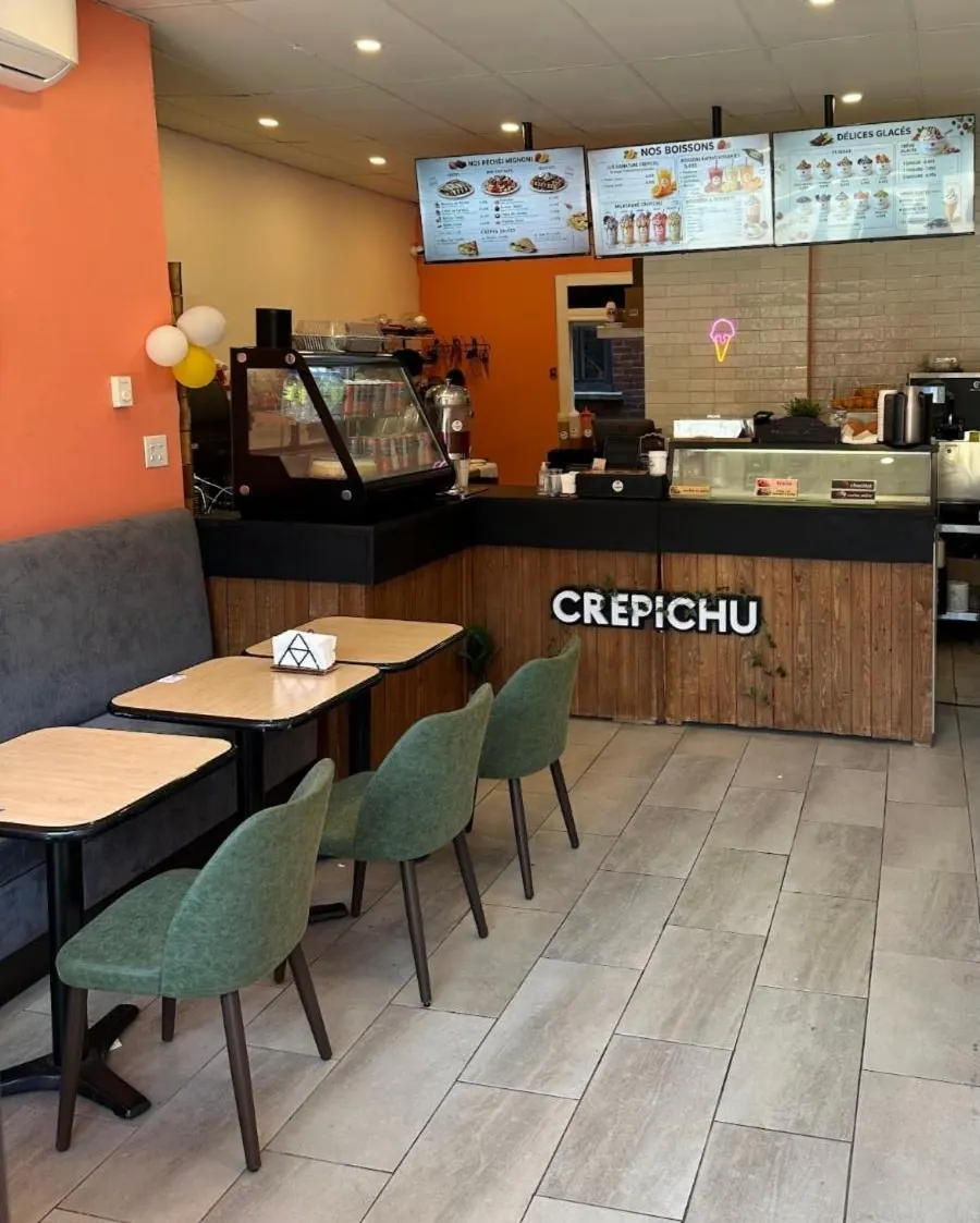 La salle de Crepichu : mur orange, chaises vertes, comptoir en bois avec le nom Crepichu et les écrans du menu